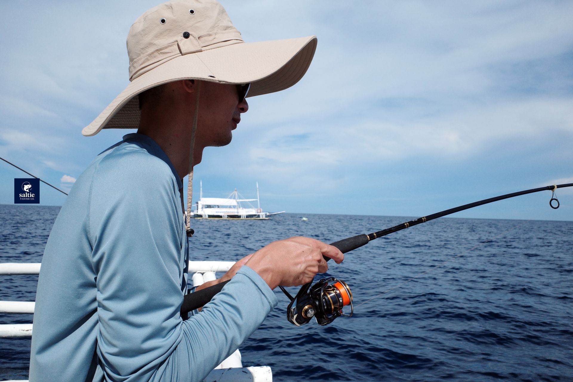 An angler holding a rod, with a banca boat in the background